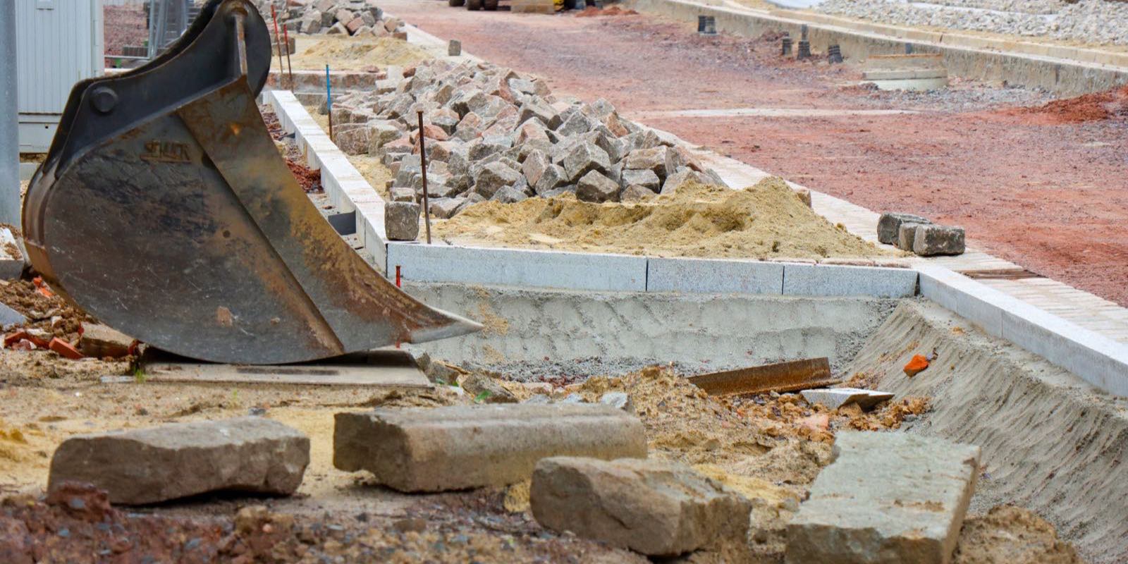 Baggerschaufel verteilt Schotter für den Unterbau einer Pflasterfläche