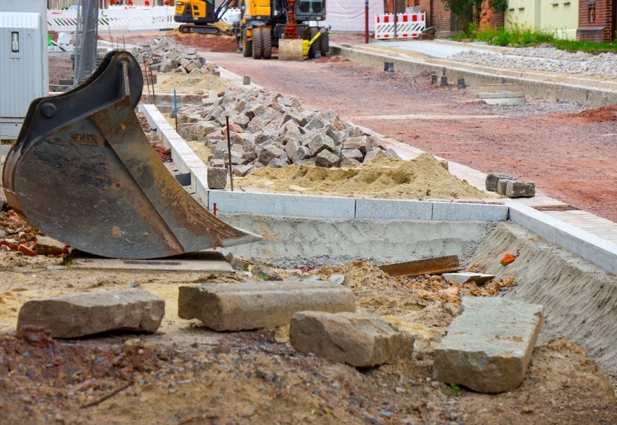 Baggerschaufel verteilt Schotter für den Unterbau einer Pflasterfläche
